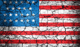 Image of an American flag on cracked pavement.